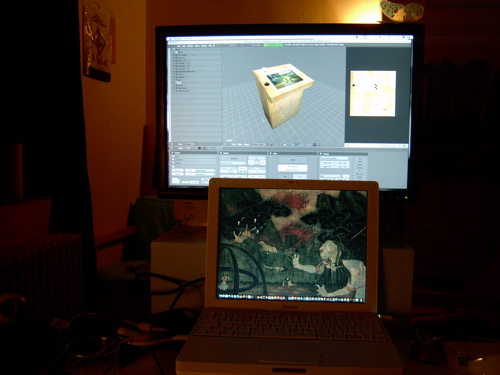Night desk: an iBook showing a dark forest painting, in front of a big monitor with Blender open on a textured cube — Endless Forest work in progress