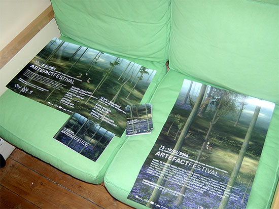 Artefact Festival 2006 posters spread on a green sofa, each showing a misty forest of tall bare trees with a tiny red figure
