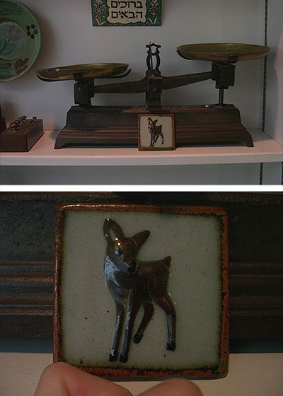 Two views of a glazed ceramic tile of a fawn: propped against an antique balance scale on a shelf, and held close-up in a hand