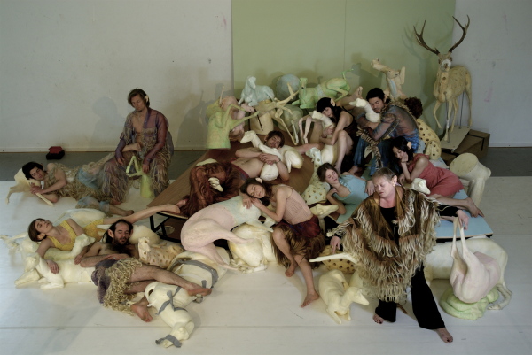 Peter Verhelst theatre tableau: performers sprawled sleeping in a heap among foam animal sculptures — deer, swans, pelicans — in fringed costumes