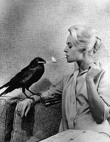Tippi Hedren lighting her cigarette from a match held in a crow's beak — The Birds publicity photo