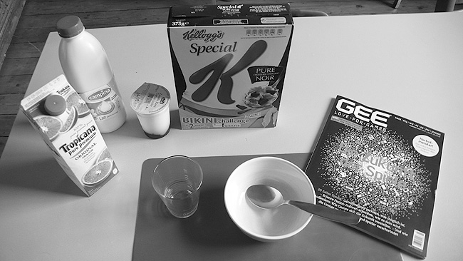 Black-and-white breakfast still life: Special K 'Bikini Challenge' box, Tropicana, milk, an empty bowl and a GEE games magazine Black-and-white breakfast still life: Special K 'Bikini Challenge' box, Tropicana, milk, an empty bowl and a GEE games magazine