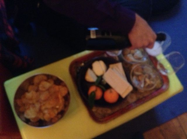 New Year's Eve tray on a yellow table: a bowl of chips, cheeses, clementines, cookies, and a hand pouring the sparkling wine New Year's Eve tray on a yellow table: a bowl of chips, cheeses, clementines, cookies, and a hand pouring the sparkling wine