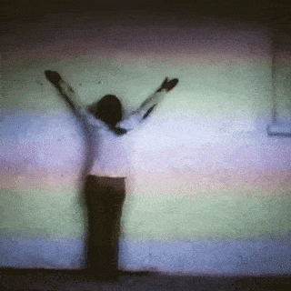 Ana Mendieta's Body Tracks: arms raised high against a pale wall at the start of the drag, blood-dipped, the film grain in rainbow bands
