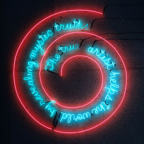 Bruce Nauman's 1967 neon spiral: 'The true artist helps the world by revealing mystic truths' in blue script wound inside a red-pink coil on a dark wall