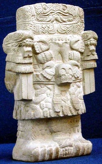 The Aztec basalt statue of Coatlicue: the earth goddess with clawed feet, a skull at her waist and twin serpent heads forming her face, on a blue ground The Aztec basalt statue of Coatlicue: the earth goddess with clawed feet, a skull at her waist and twin serpent heads forming her face, on a blue ground