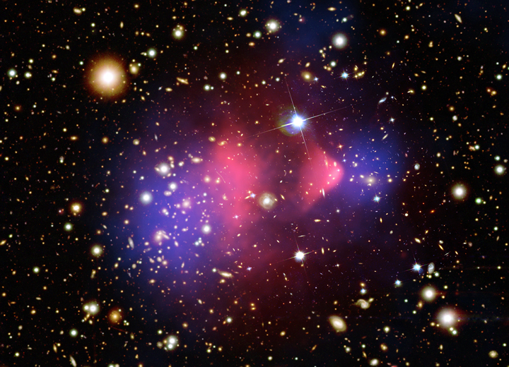 Composite telescope image of the Bullet Cluster: colliding galaxy clusters with hot gas in pink and the inferred dark matter mapped in blue among the field of galaxies