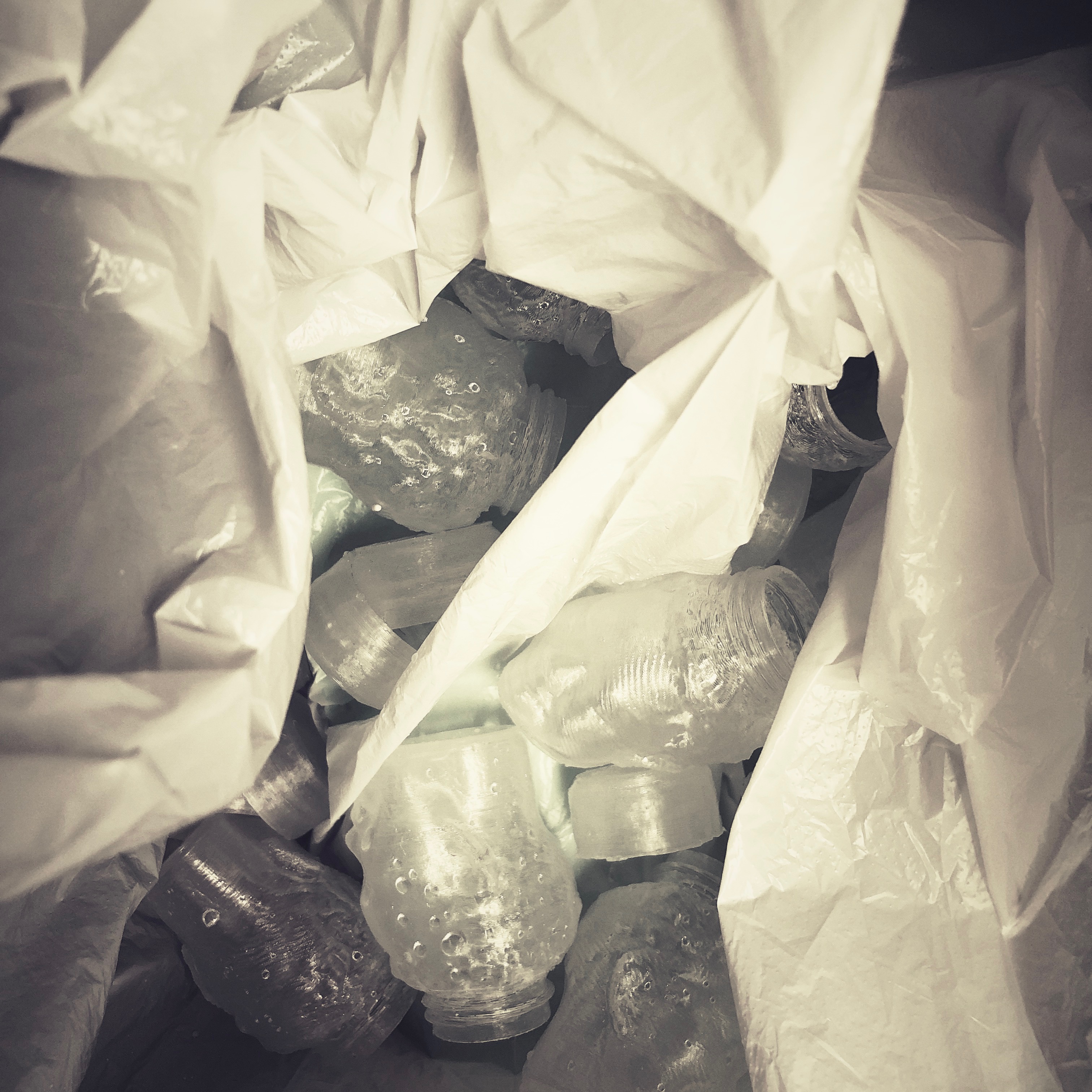 A tissue-lined box packed with translucent 3D-printed head-shaped bottles, their screw necks rising from the crowns like bottle caps