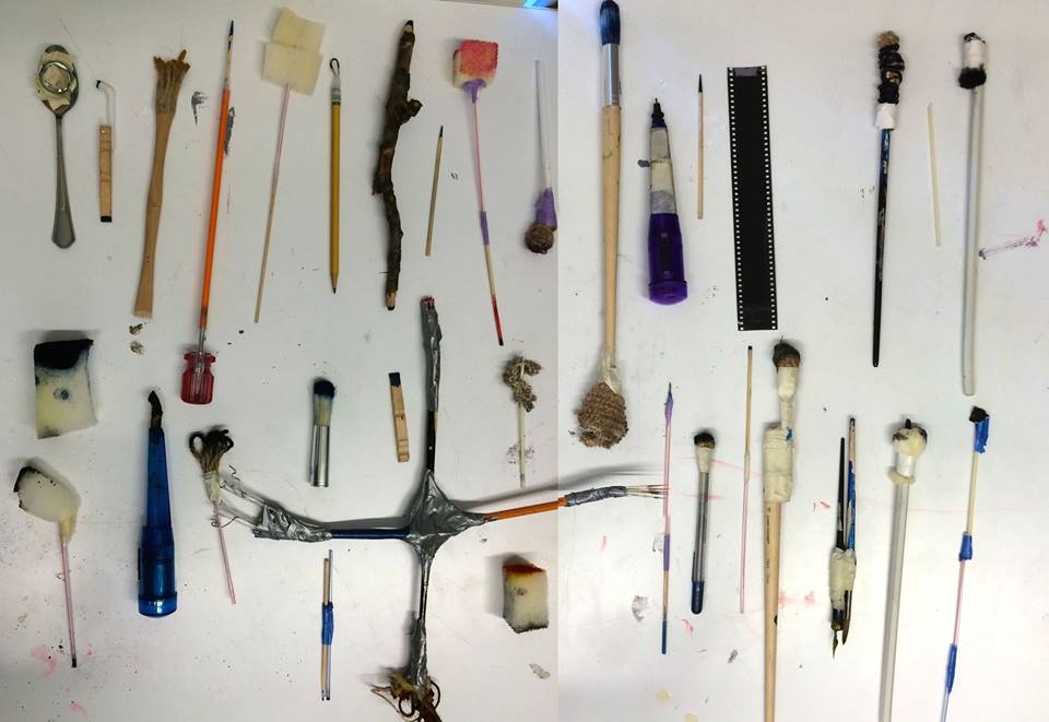 Handmade drawing tools made by Henrik Drescher's students laid out on white: spoons, sticks, sponge-tipped rods, taped filmstrip, feathers and bound rag brushes