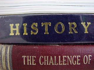 Two stacked book spines misread as one phrase: gold-stamped HISTORY above a red cloth spine reading THE CHALLENGE OF