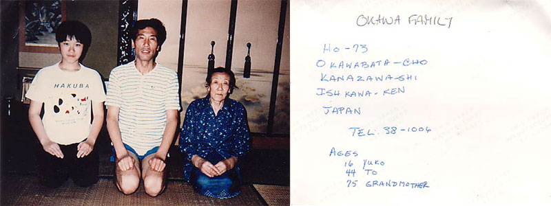 Homestay snapshot from Kanazawa: the Okawa family — teenage son, father and grandmother — kneeling on tatami, beside the envelope back with their family details handwritten