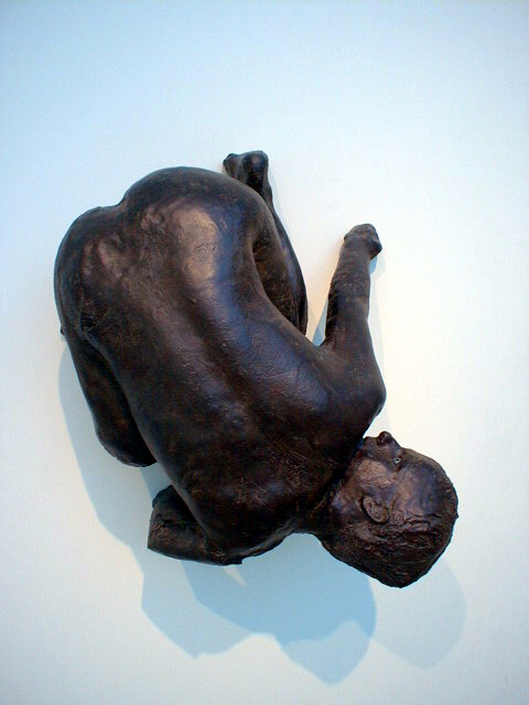 Kiki Smith's Lilith: a black bronze woman cast from life, crouching upside down high on the gallery wall, glass eyes looking back over her shoulder