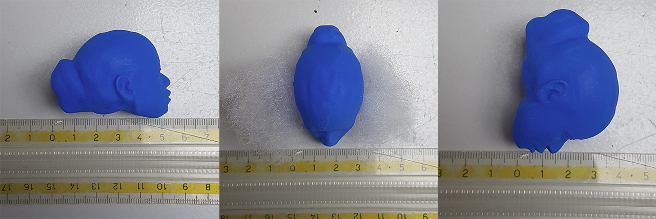 Three views of the Object 01 head 3D-printed in blue wax beside a ruler, about five centimeters long, seen in profile, from above, and three-quarter