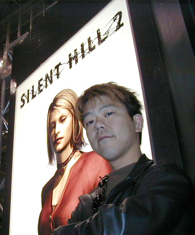 Takayoshi Sato with arms crossed in a leather jacket beneath a glowing Silent Hill 2 banner where Maria poses in her red top