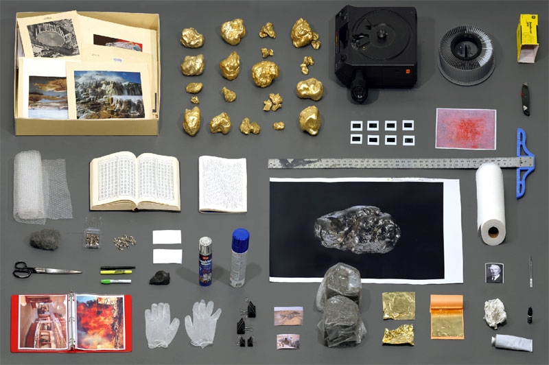 Daniel Lefcourt's The Invention of Public Relations: gold-painted nuggets, a slide projector and carousel, rulers, gloves, and archive photos knolled on grey