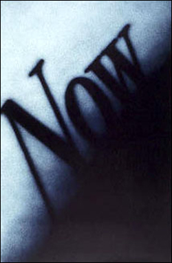 The word NOW in soft-edged black letters, set diagonally and dissolving into a pale blue ground