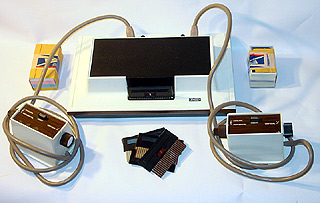A Magnavox Odyssey, the first home video game console: white unit with two cable-tethered paddle controllers, game cards, and boxed accessories