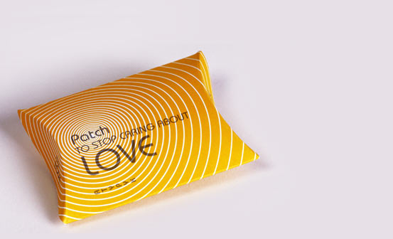 Yellow pillow-box package printed with concentric white rings: Patch to stop caring about love