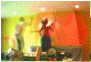 Tiny blurred frame of figures dancing in a room washed green and yellow